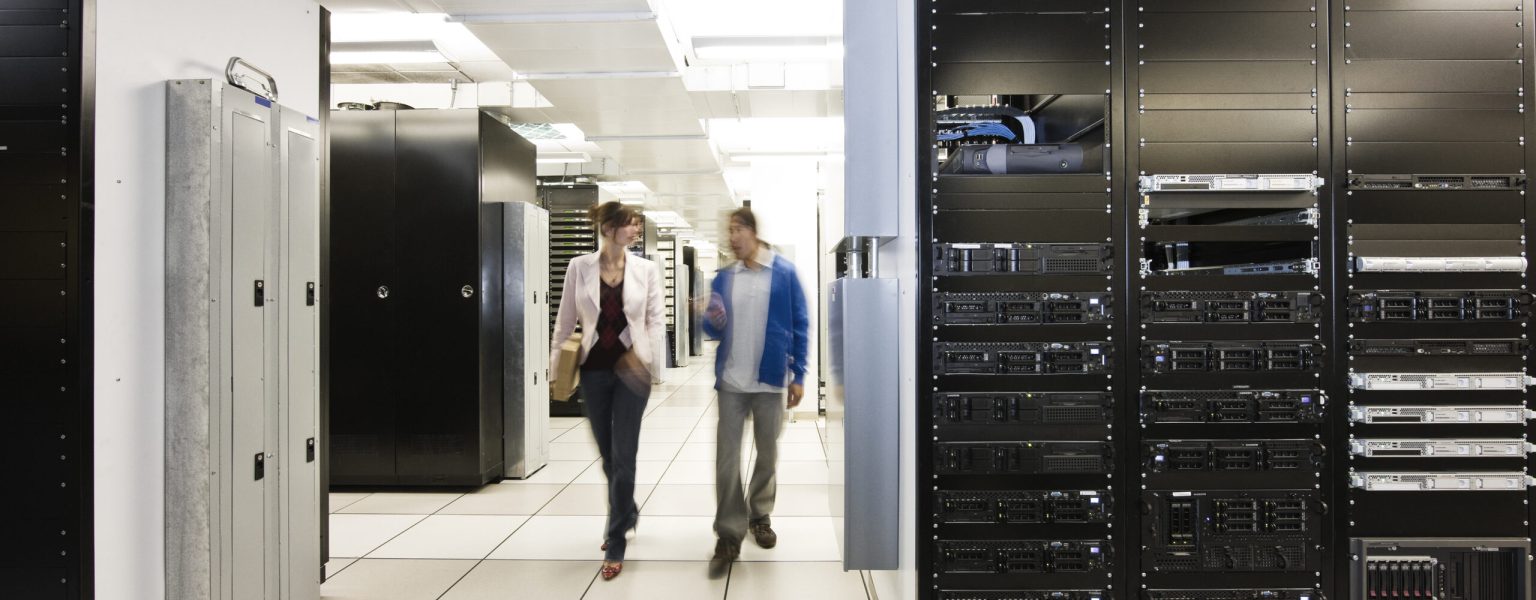 Computer server room racks with technician in background. Computer server room racks with technician in background.