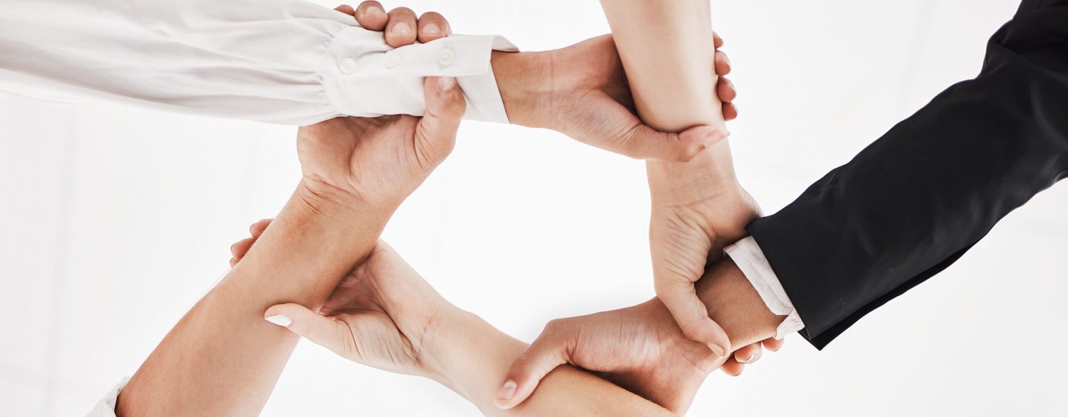 teamwork Low angle shot of a group of businesspeople holding one anothers wrists in a circular formation.